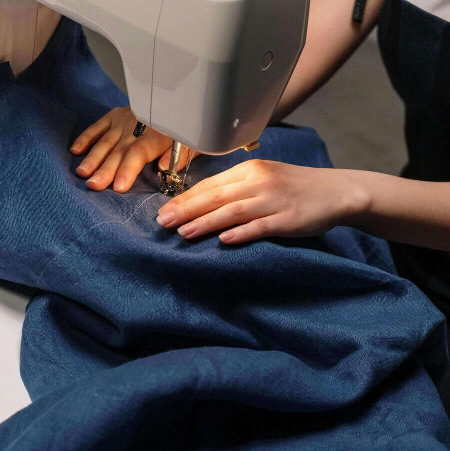 Person using a sewing machine on blue fabric